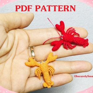 Puede incluir: Dos langostas en miniatura tejidas a ganchillo, una de color rojo brillante y otra naranja, cada una con pequeños ojos negros y pinzas detalladas. El texto PDF PATTERN aparece arriba y el texto ObscurelySmall se ve abajo a la derecha.