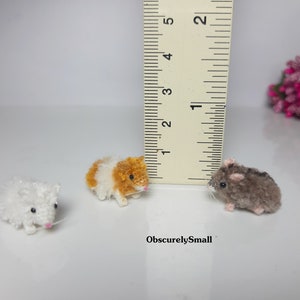 May include: Three small, handmade hamster plushies. The plushies are made of yarn and are about 1 inch tall. The plushies are white, brown and orange.