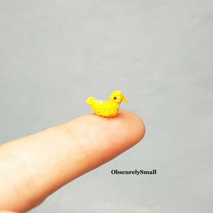 May include: A tiny yellow crocheted duckling, about the size of a fingertip, is perched on a finger.