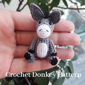 Puede incluir: Un peque&ntilde;o burro de crochet gris con pezu&ntilde;as negras y una crin negra. El burro est&aacute; sentado en una mano.