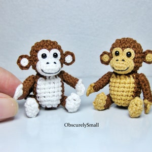 May include: Two crocheted monkey toys, one with brown fur and white accents, the other with brown fur and tan accents. Both monkeys have black eyes and a smiling expression.
