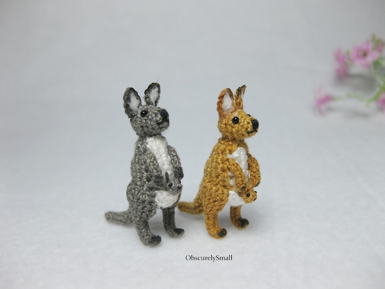 May include: Two crocheted kangaroo toys, one gray and one brown, both holding a smaller crocheted joey in their pouch.