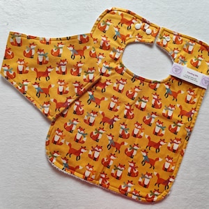 May include: A yellow bib with a fox print and a matching burp cloth. The bib has a snap closure and the text "Sewing Bib" is printed on the cloth.