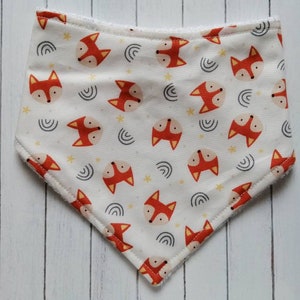 May include: White bandana with a fox print. The bandana has a white background with orange fox faces, yellow stars, and gray curved lines.