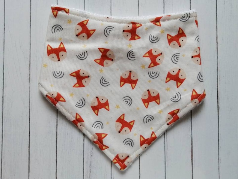 May include: White bandana with a fox print. The bandana has a white background with orange fox faces, yellow stars, and gray curved lines.