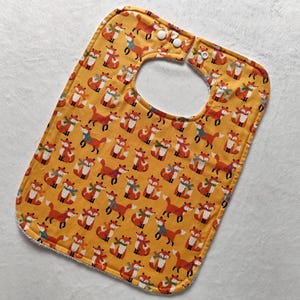 May include: A yellow baby bib with a fox print. The bib has two white snaps on the neck.