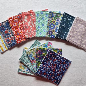 May include: A set of 16 reusable cotton makeup remover pads with various floral patterns in shades of blue, green, pink, and purple. The pads are arranged in a semi-circle with a few stacked on top of each other.