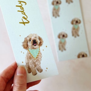 May include: Two light blue bookmarks with gold ribbon. One bookmark features a watercolor illustration of a poodle wearing a turquoise bandana, with the name "Teddy" in gold script. The other bookmark has a repeating pattern of the poodle illustration.