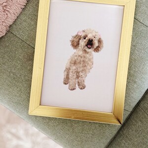 May include: A framed illustration of a light brown poodle with pink bows on its ears. The poodle is standing on a white background.