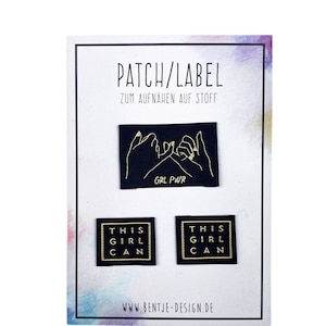 Könnte beinhalten: Drei Bügelbilder mit goldener Schrift auf schwarzem Hintergrund. Das obere Bügelbild zeigt zwei Hände, die sich einen kleinen Finger versprechen, mit dem Text "GRL PWR". Die beiden unteren Bügelbilder sind quadratisch und zeigen den Text "THIS GIRL CAN".