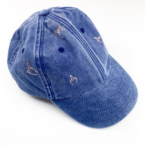 Könnte beinhalten: Eine blaue Baseballkappe aus Denim mit vier gestickten Mittelfingern in Kupfer.
