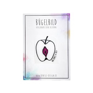 Könnte beinhalten: Bügelbild mit einem schwarzen und weißen Umriss eines Apfels mit einem rosafarbenen Zentrum. Der Text "An apple a day" ist auf den Apfel geschrieben. Das Bügelbild befindet sich auf einer weißen Karte mit dem Text "Bügelbild" und "Verschönere deine Kleidung" in Schwarz.