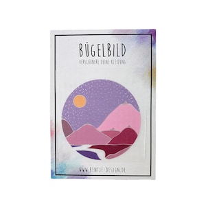 Könnte beinhalten: Ein runder Bügelbild-Aufnäher in Lila und Rosa mit einem Berglandschaft-Design. Der Aufnäher ist rund und hat einen weißen Rand. Der Text "BÜGELBILD" und "VERSCHÖNERE DEINE KLEIDUNG" ist auf der Karte gedruckt. Der Text "WWW.BENTJE-DESIGN.DE" ist unten auf der Karte gedruckt.
