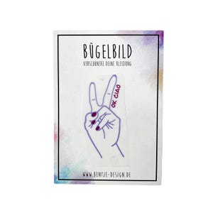 Könnte beinhalten: Bügelbild mit einer lila Peace-Hand mit pinkfarbenen Fingernägeln und dem Text "OK CIAO" in Rot.