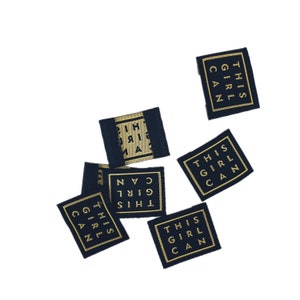 Könnte beinhalten: Fünf schwarze Stoff-Etiketten mit goldener Aufschrift "This Girl Can".