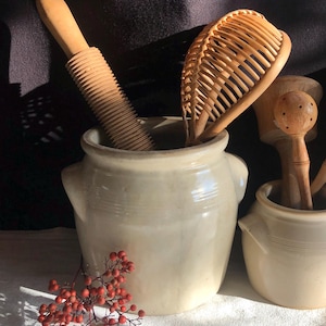 May include: A white ceramic mug with a black handle and the text "But First, Coffee" in a black, handwritten-style font. The mug is on a white surface.