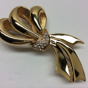 May include: A gold-toned bow brooch with clear rhinestones in the centre.