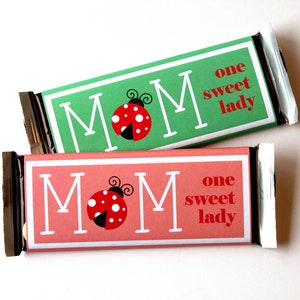 May include: Two chocolate bar wrappers with a green and pink background. Each wrapper has a ladybug graphic and the text "MOM" and "one sweet lady".