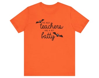 Könnte beinhalten: Orangefarbenes T-Shirt mit schwarzem Text, der "The best teachers are a bit batty" lautet, mit zwei schwarzen Fledermäusen auf beiden Seiten des Textes.