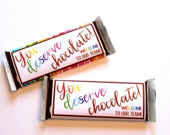 May include: Two chocolate bars wrapped in silver foil with colorful labels that say "You deserve chocolate!" and "Welcome to our team!"