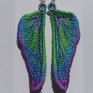 May include: A pair of dangle earrings featuring a wing design. The wings are crafted from blue, green and purple fabric with a silver wire loop at the top.