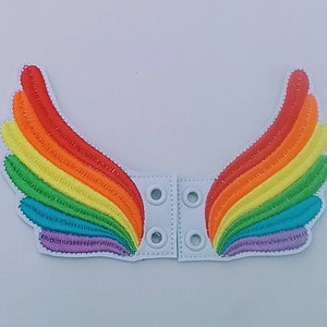 May include: Embroidered rainbow wing patches with a white backing. The wings feature a vibrant spectrum of colors, including red, orange, yellow, green, blue, and purple. Each wing has a white base with snap closures.