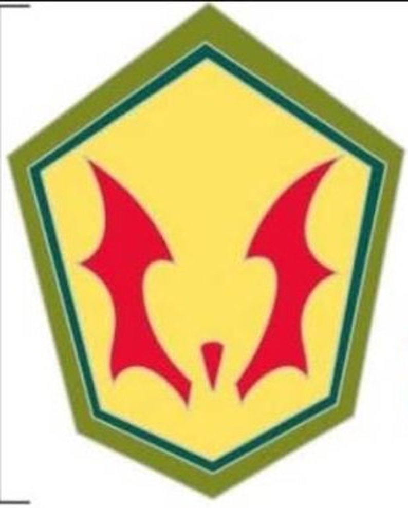 May include: A yellow pentagon-shaped emblem with a red bat-like symbol in the center. The emblem has a green border and is set against a white background. The bat symbol has two wing-like shapes.