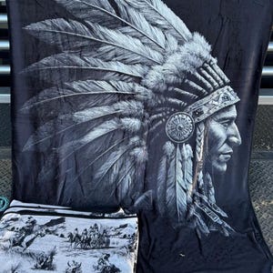 May include: Black blanket featuring a detailed grayscale image of a Native American chief in profile, wearing a feathered headdress. A smaller blanket with a black and white scene of Native Americans is also visible.