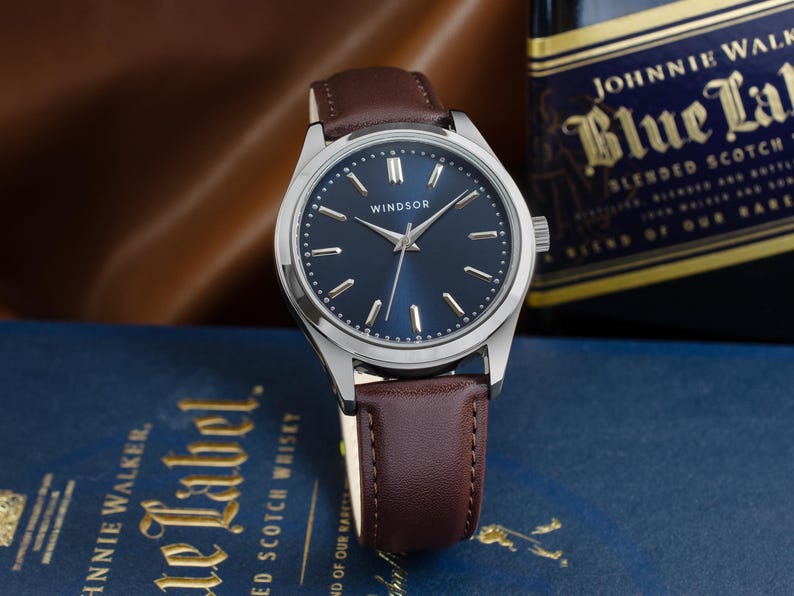 May include: A silver wristwatch with a blue face and brown leather band. The watch face has silver hands and markers, and the word "WINDSOR" is printed in the center.