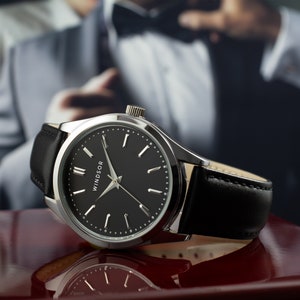 May include: A silver watch with a black leather band and a black face. The watch face has silver hands and Roman numeral hour markers. The word "WINDSOR" is printed on the face.