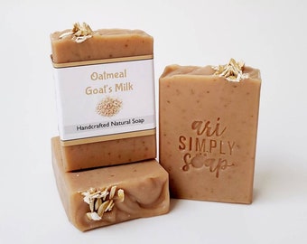 May include: Three bars of handmade oatmeal goat's milk soap. The top bar has a label that reads "Oatmeal Goat's Milk Handcrafted Natural Soap". The bottom bar has the words "ari SIMPLY soap" stamped on it.