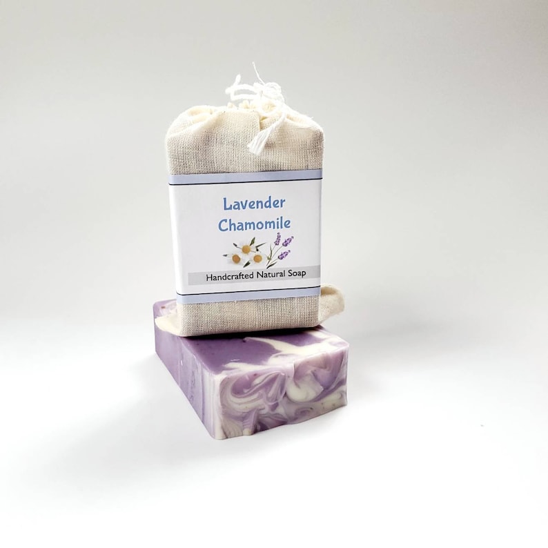 May include: A bar of lavender and chamomile soap wrapped in a natural fabric bag. The soap is a swirl of purple and white and the label reads "Lavender Chamomile Handcrafted Natural Soap".