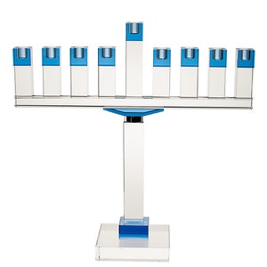 Puede incluir: Una menorá de cristal con nueve candelabros, cada uno con una parte superior de vidrio azul. La menorá tiene una base de cristal transparente y un tallo central.