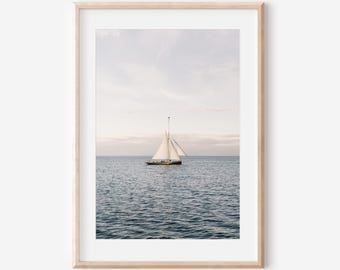 May include: A white sailboat with sails unfurled, sailing on a calm blue ocean under a cloudy sky.