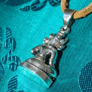 May include: Silver pendant featuring a detailed sculpture of a seated figure. The pendant is attached to a brown leather cord and has a 925 stamp on the back.