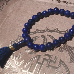 May include: A blue lapis lazuli mala prayer bead necklace with a blue tassel.