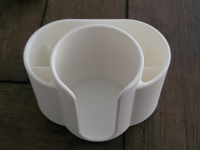 May include: White plastic desk organizer with a cup holder and compartments for pens and pencils.