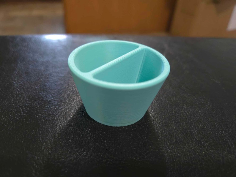 May include: A light blue divided dish made of plastic. The dish has a rounded shape and a smooth surface.