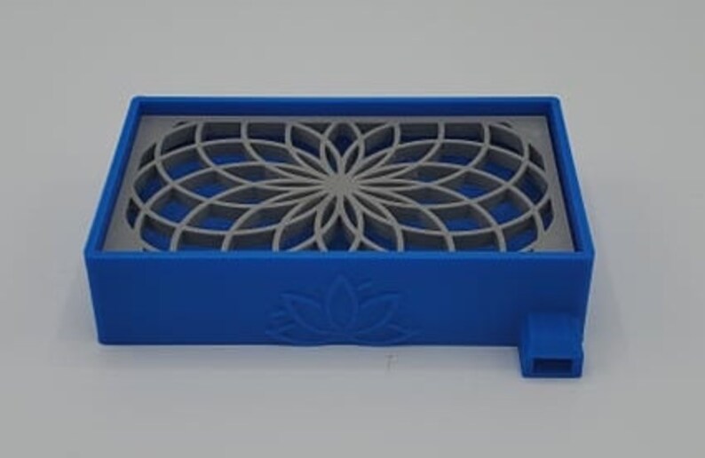 Puede incluir: Una bandeja de pl&aacute;stico azul con un dise&ntilde;o geom&eacute;trico recortado. La bandeja tiene un dise&ntilde;o de flor de loto en la parte inferior y un peque&ntilde;o pico en el lateral.