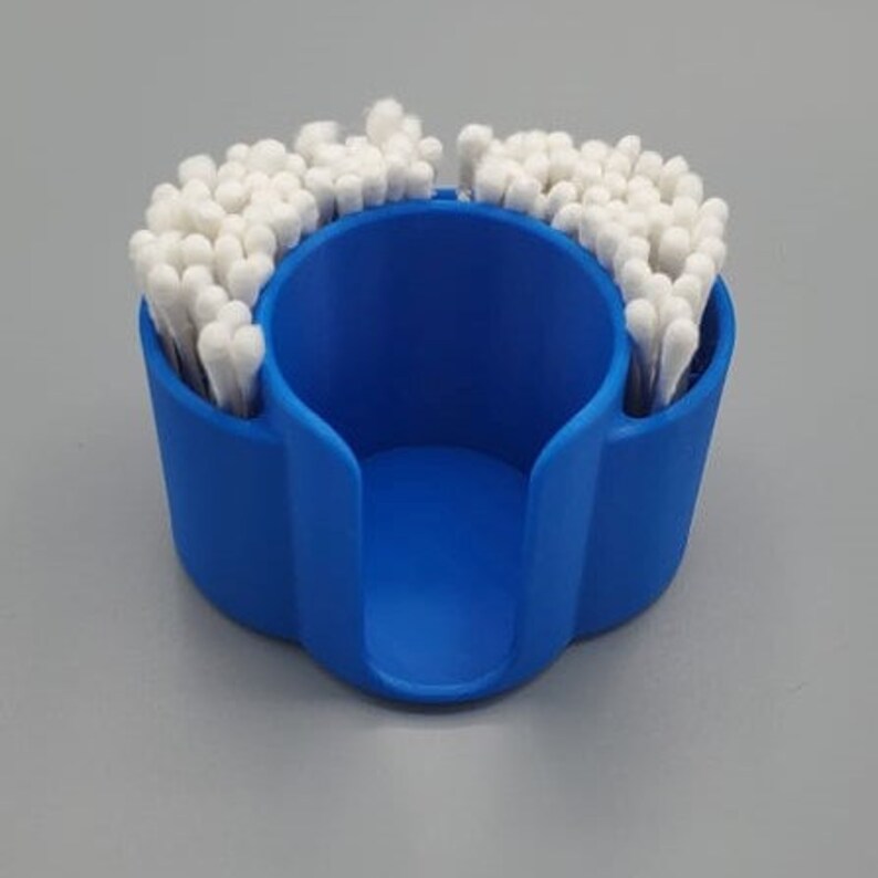 May include: A blue plastic cotton swab holder with a circular opening in the center. The holder is filled with cotton swabs.