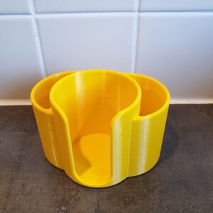 May include: A yellow plastic kitchen countertop organizer with three compartments for storing items like sponges, brushes, or dishcloths.