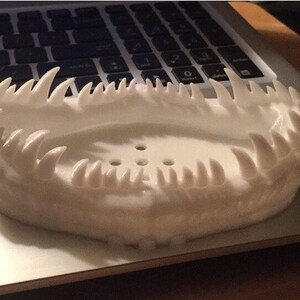 May include: White 3D printed soap dish with a jagged, tooth-like design around the rim.
