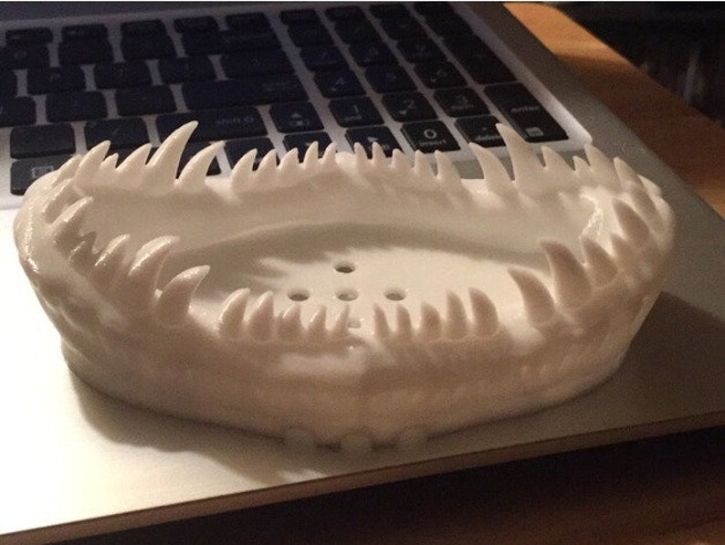 May include: White 3D printed soap dish with a jagged, tooth-like design around the rim.