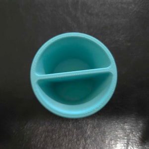 May include: A divided turquoise blue ceramic dish with a rounded shape. The dish has two sections.