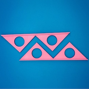 May include: Pink plastic protractor with four circles cut out. The protractor is on a blue background.
