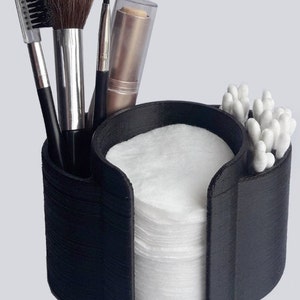 May include: Black plastic makeup organizer with compartments for cotton rounds, cotton swabs, and makeup brushes.