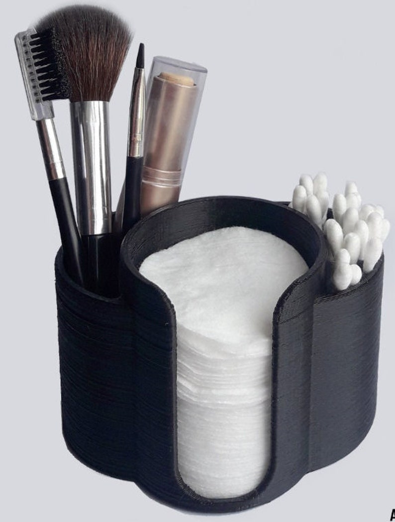 May include: Black plastic makeup organizer with compartments for cotton rounds, cotton swabs, and makeup brushes.