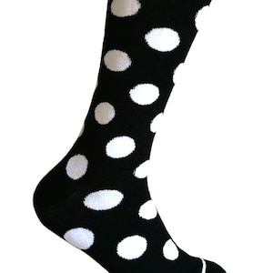 May include: Black sock with large white polka dots. The sock is knee-high and has a white stripe around the toe. The polka dots are evenly spaced across the sock.
