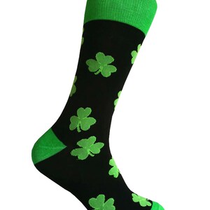 May include: Black socks with a green shamrock pattern. The socks have a green cuff.