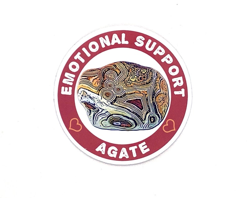 May include: A red circular sticker with the text "Emotional Support Agate" in white lettering. The sticker features a heart on each side of the text and a colourful agate stone in the centre.